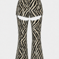 Zebra-print flared pants with a high-waisted design and large leg cutouts, shown against a plain light gray background.